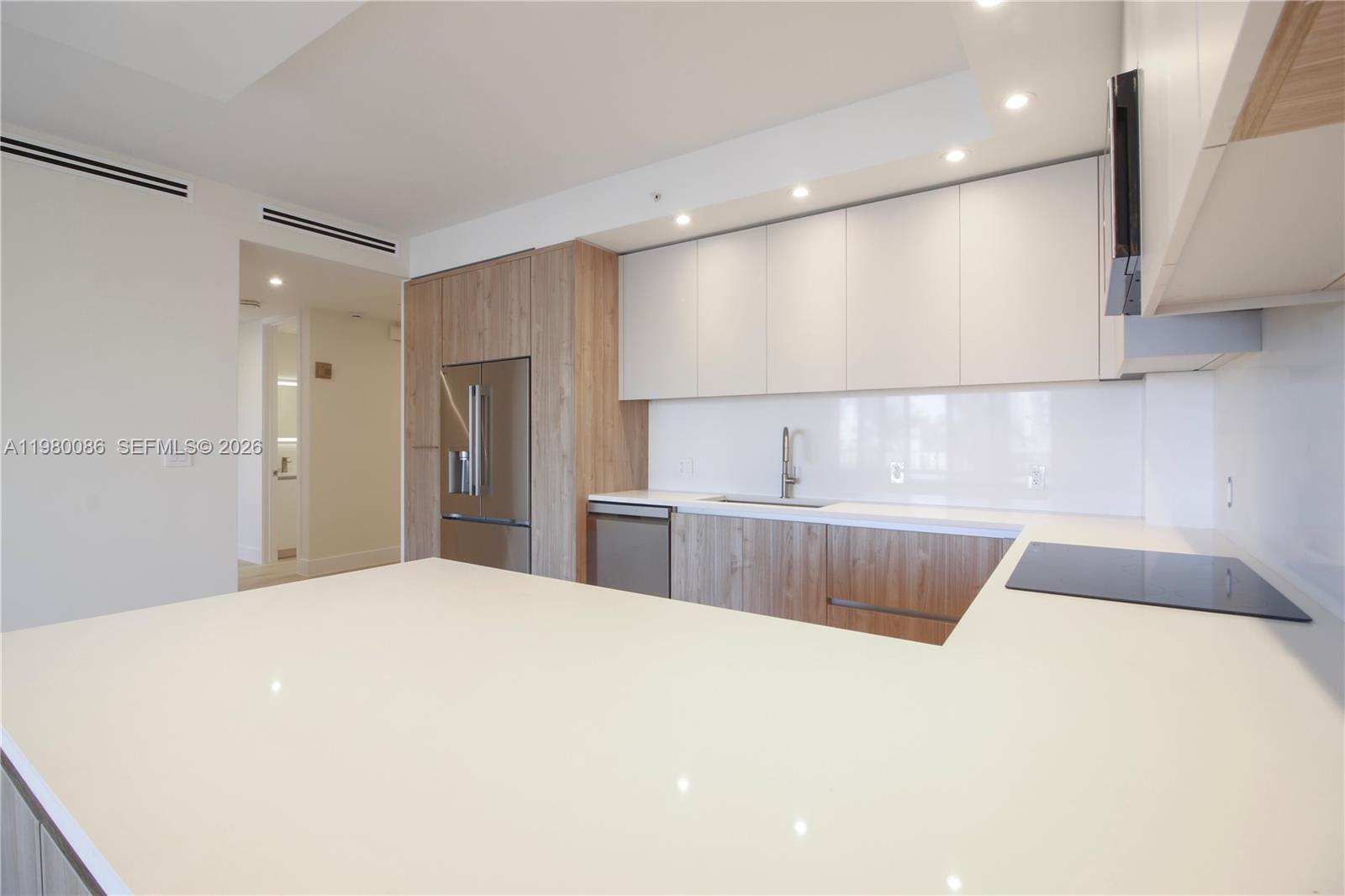 151 Crandon Boulevard, Unit 540 Key Biscayne, FL 33149 - Photo 17 of 41 a large white kitchen with kitchen island granite countertop a sink and a refrigerator