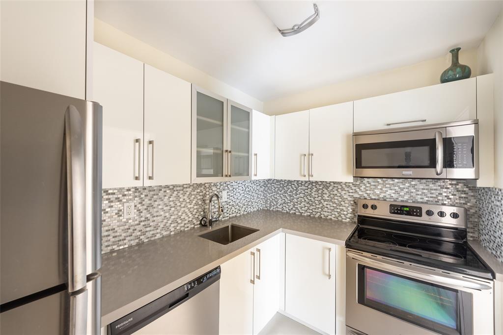 7925 Southwest 104th Street, Unit 203E Miami, FL 33156 - Photo 7 of 23 a kitchen with stainless steel appliances a stove microwave and refrigerator