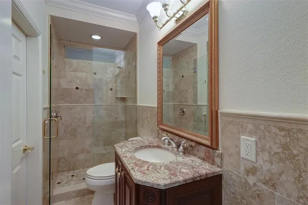 a bathroom with a granite countertop sink a toilet and a shower
