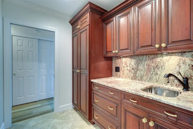 a kitchen with stainless steel appliances granite countertop a sink a washer and dryer with wooden cabinets