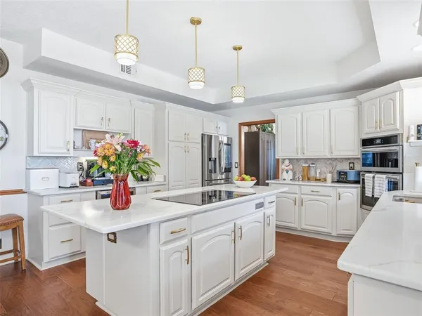 a kitchen with kitchen island granite countertop a sink a counter space appliances and cabinets