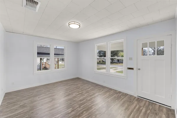a view of an empty room with a window and wooden floor