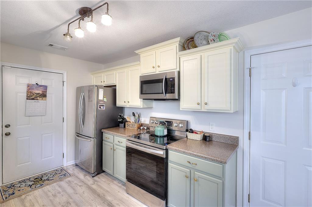 148 Alice Walker Drive Athens, GA 30607 - Photo 11 of 28 a kitchen with stainless steel appliances granite countertop a refrigerator a stove a sink and white cabinets with wooden floor