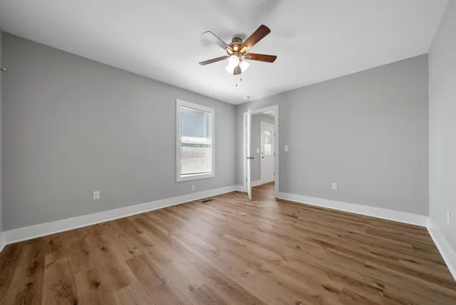an empty room with wooden floor and ceiling fan