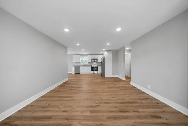 a view of empty room with kitchen and window