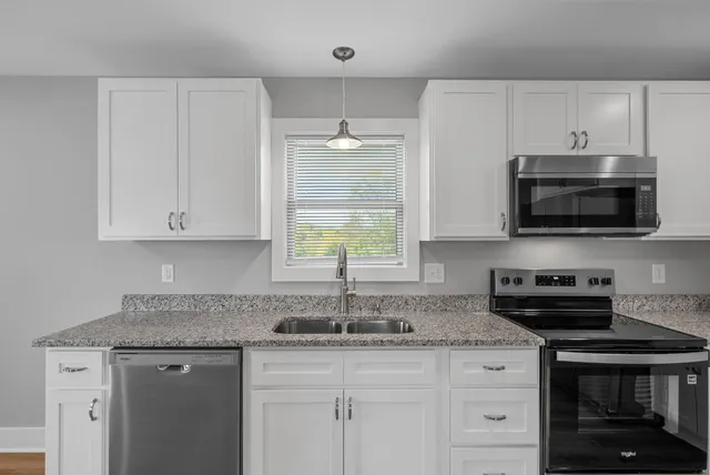 a kitchen with stainless steel appliances granite countertop a sink a stove a microwave and wooden cabinets