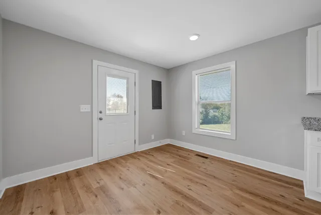 an empty room with wooden floor and windows