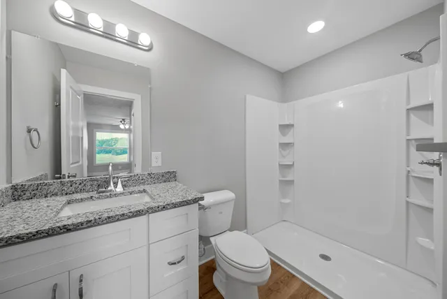 a bathroom with a granite countertop sink a toilet and shower