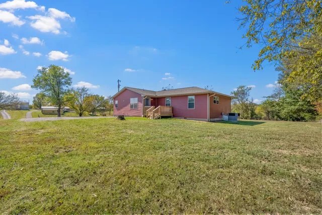 a front view of house with yard and trees in the background