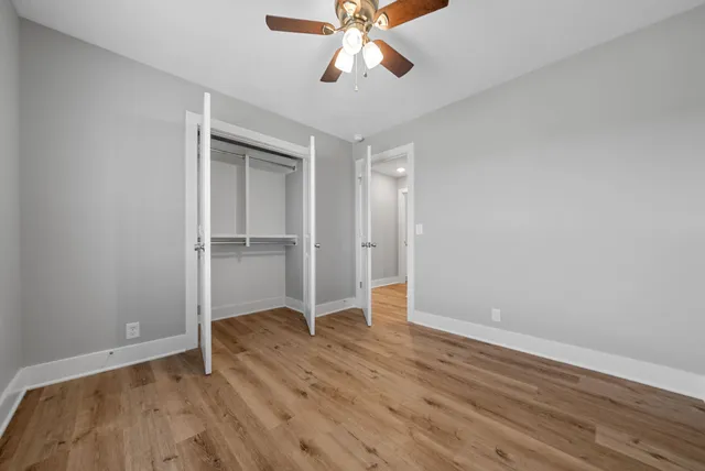 an empty room with wooden floor closet and windows