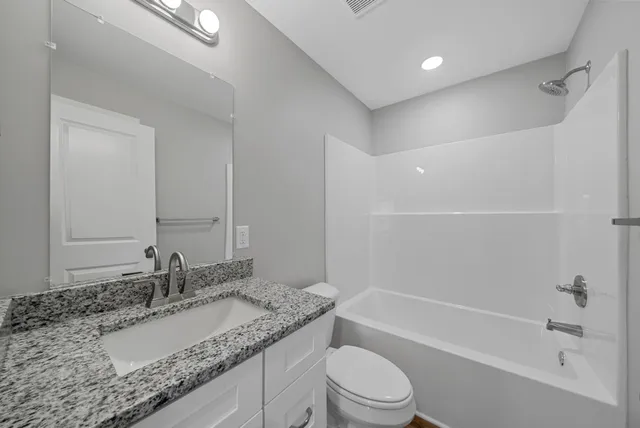 a bathroom with a granite countertop sink a mirror and a bathtub