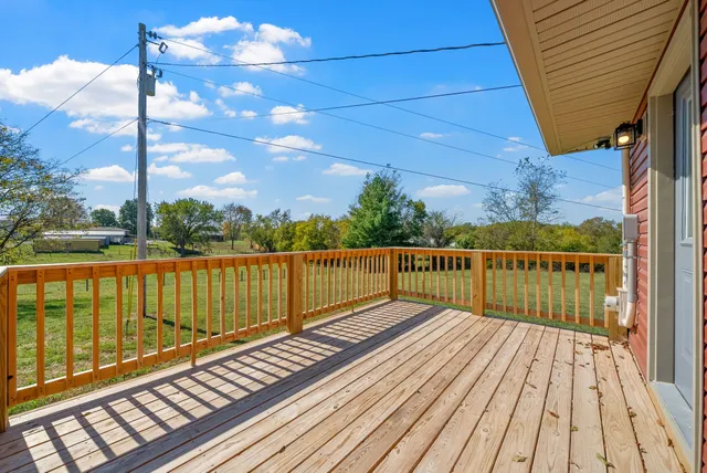 a balcony with wooden floor next to a yard
