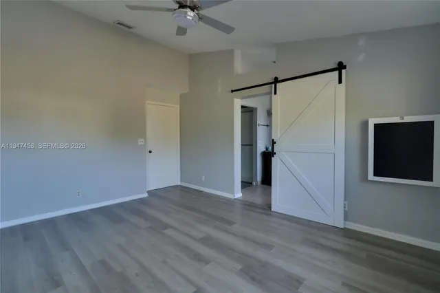 an empty room with wooden floor and a ceiling fan