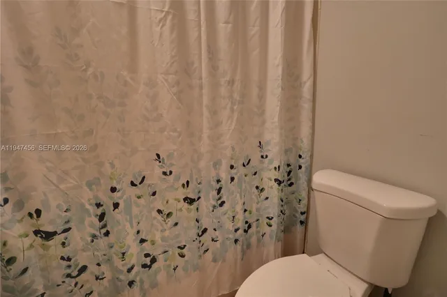a white toilet sitting next to a shower curtain