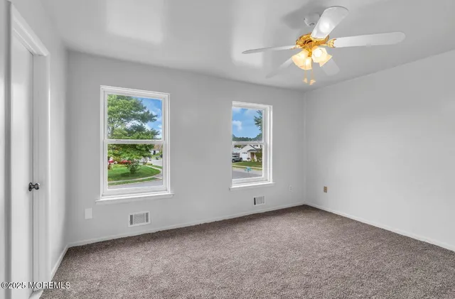 an empty room with windows and chandelier fan