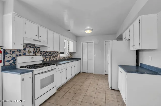 a kitchen with granite countertop white cabinets and white appliances