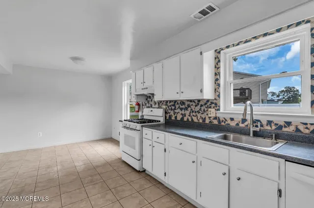 a kitchen with granite countertop white cabinets and sink