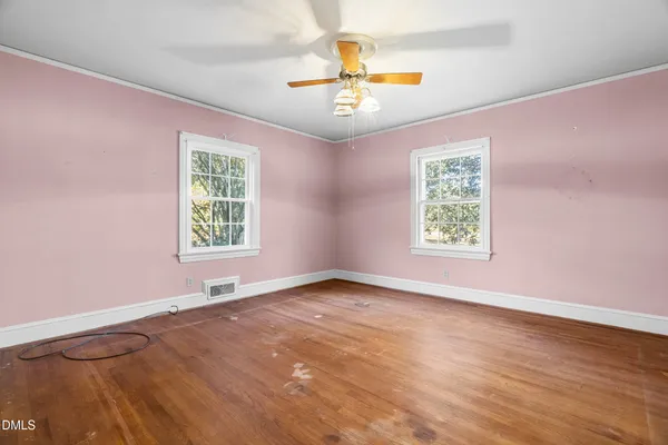 an empty room with windows and chandelier fan