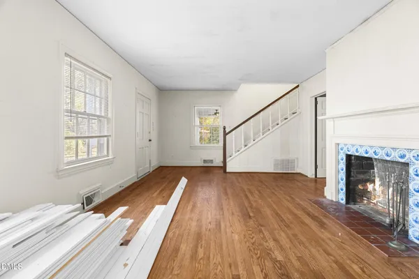 a view of an empty room with wooden floor fireplace and a window