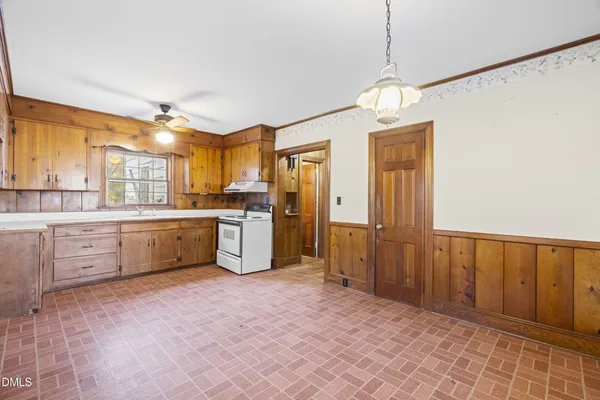 a large white kitchen with window and a refrigerator
