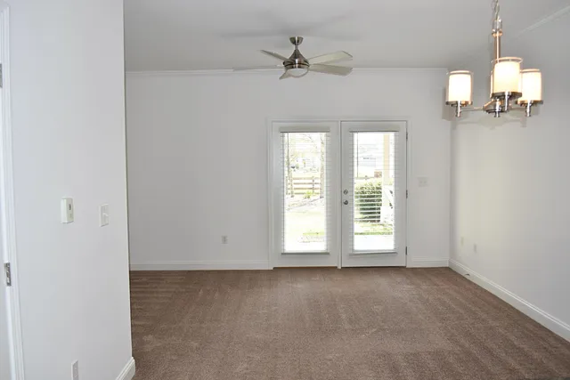 an empty room with windows and ceiling fan