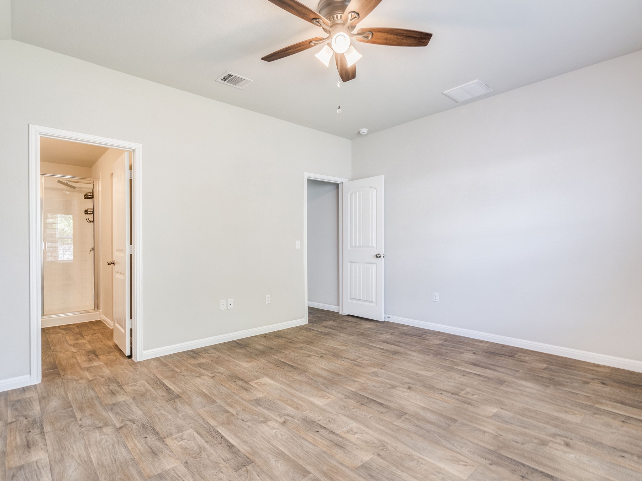136 Dunlin Lane Leander, TX 78641 - Photo 12 of 24 Unfurnished bedroom with ceiling fan, light wood finished floors, and ensuite bathroom