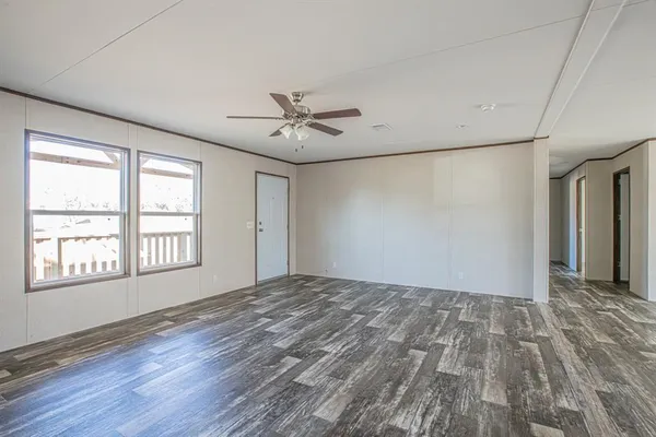 a view of an empty room with a window and wooden floor