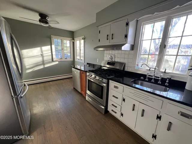a kitchen with granite countertop a stove a sink and a refrigerator