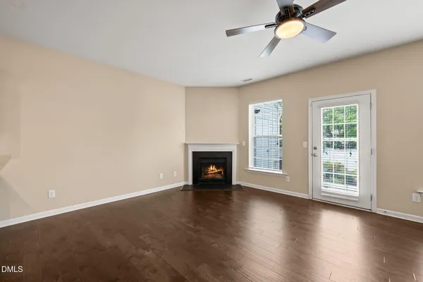 an empty room with wooden floor fireplace and windows
