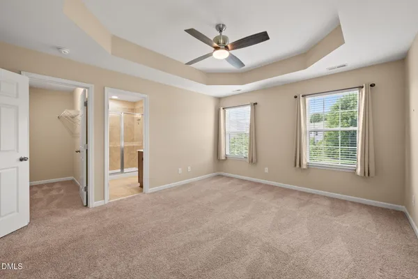 a view of a livingroom with a ceiling fan & windows