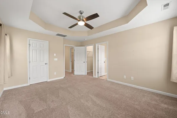 an empty room with ceiling fan and windows
