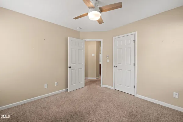 an empty room with closet and a chandelier fan