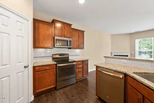 a kitchen with stainless steel appliances granite countertop a stove a sink and a microwave