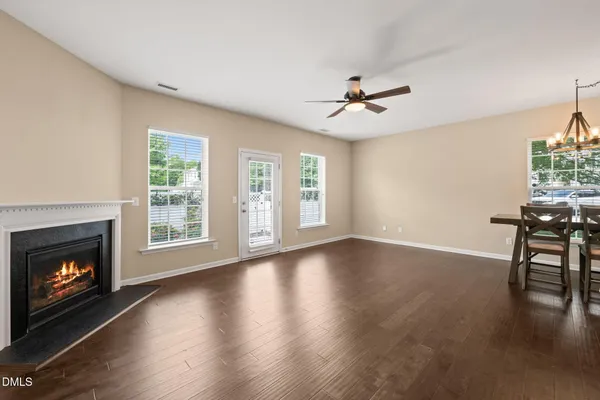 a view of an empty room with wooden floor fireplace and a window