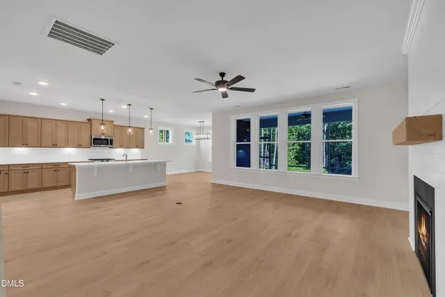 a view of an empty room with a kitchen and a window
