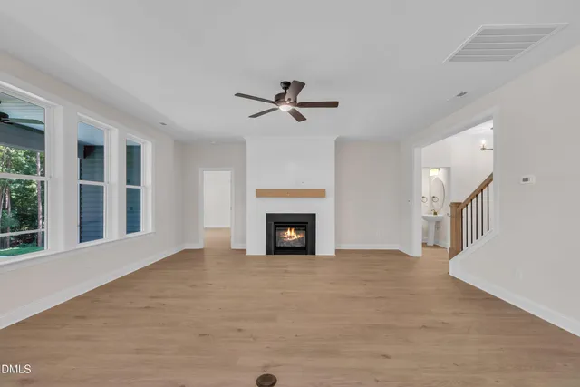 a view of a livingroom with a fireplace a ceiling fan and a fireplace
