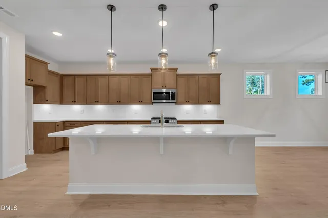 a large kitchen with stainless steel appliances granite countertop a sink a stove a refrigerator a center island a stove and a window with wooden floor