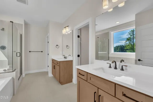 a bathroom with a sink double vanity granite tub shower and a mirror