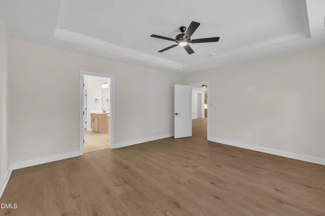 a view of empty room with wooden floor and ceiling fan