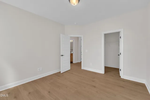 a view of an empty room with wooden floor and window