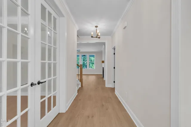 a view of a hallway with wooden floor and a bathroom