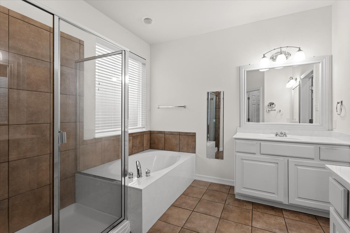 2304 Village View Loop Pflugerville, TX 78660 - Photo 27 of 40 The primary bathroom features a generous soaking tub, a separate glass-enclosed shower, and a broad vanity with abundant counter space.