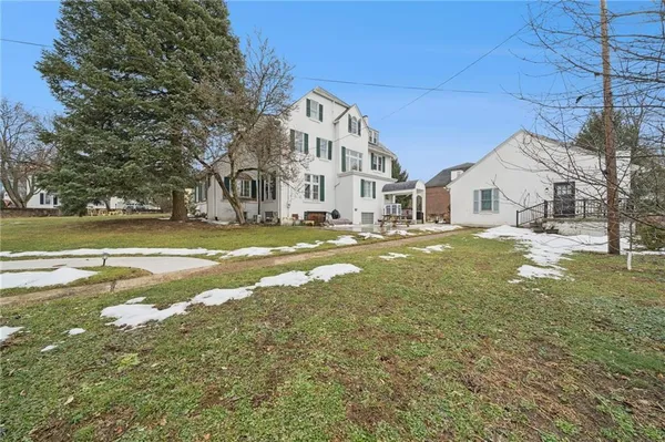 a view of a big house with a big yard and large trees