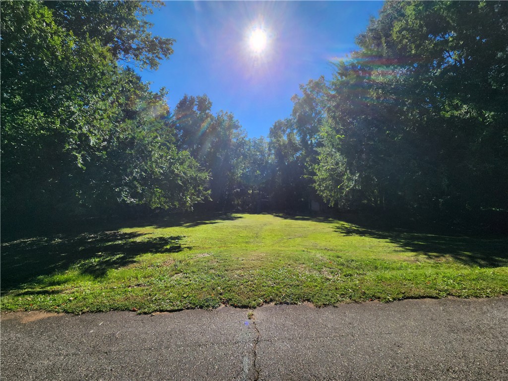 0 Henry Street Easley, SC 29640 - Photo 1 of 5 Mature trees border a spacious, grassy clearing under a sunny sky.