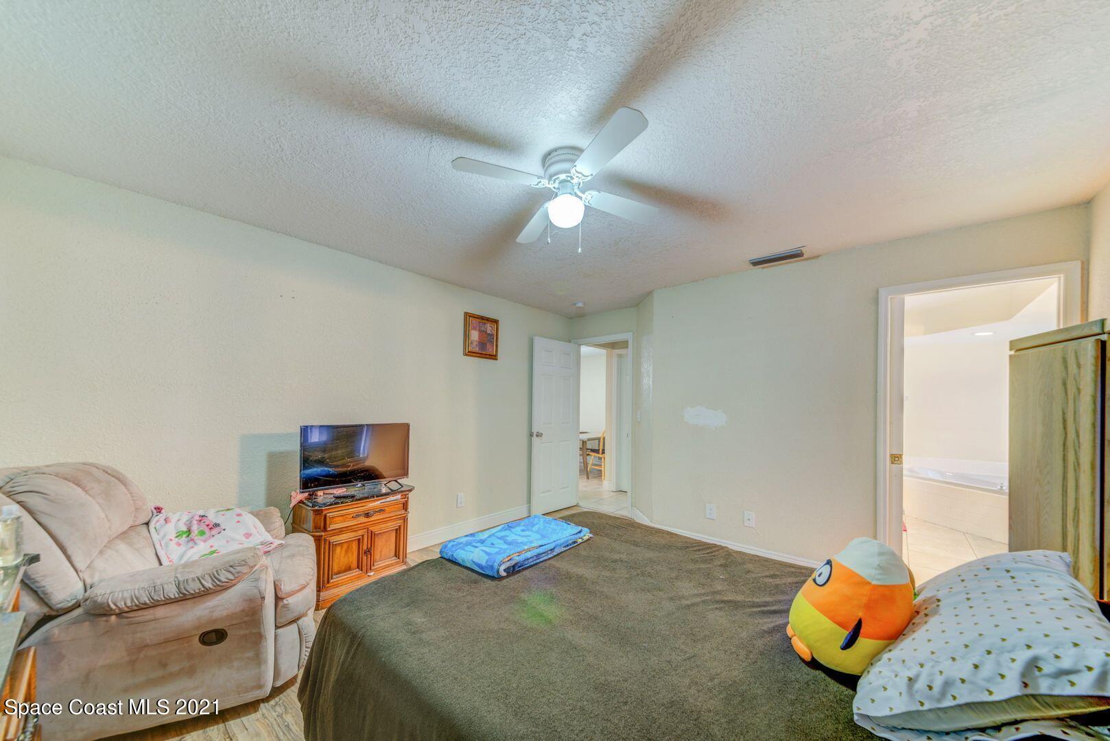 6025 Adina Road Cocoa, FL 32927 - Photo 14 of 22 a bedroom with a bed and a chandelier