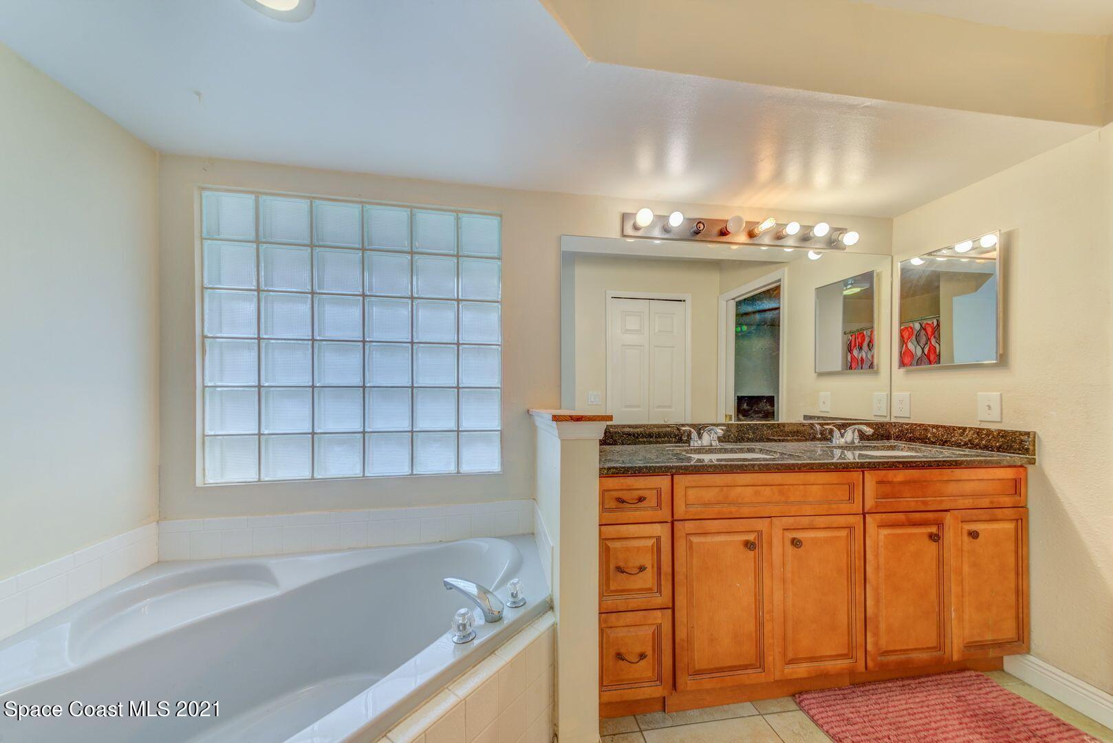 6025 Adina Road Cocoa, FL 32927 - Photo 20 of 22 a spacious bathroom with a granite countertop sink and a mirror