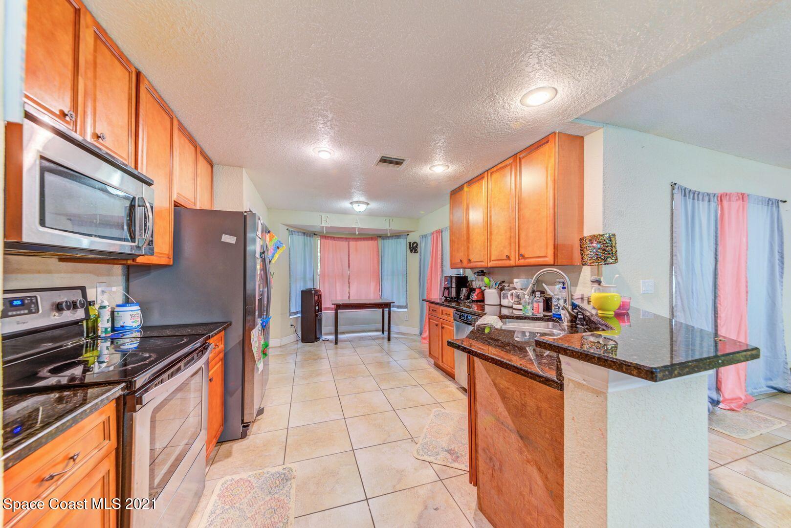 6025 Adina Road Cocoa, FL 32927 - Photo 9 of 22 a kitchen with stainless steel appliances a sink stove and cabinets