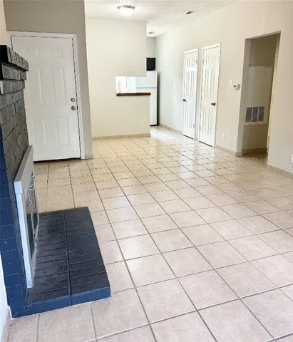 a view of a refrigerator in kitchen and an empty room with wooden floor