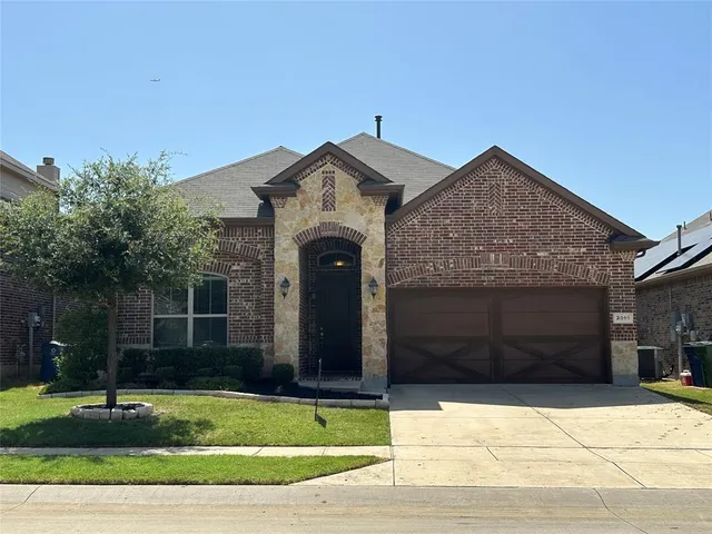 a front view of a house with garage and plants