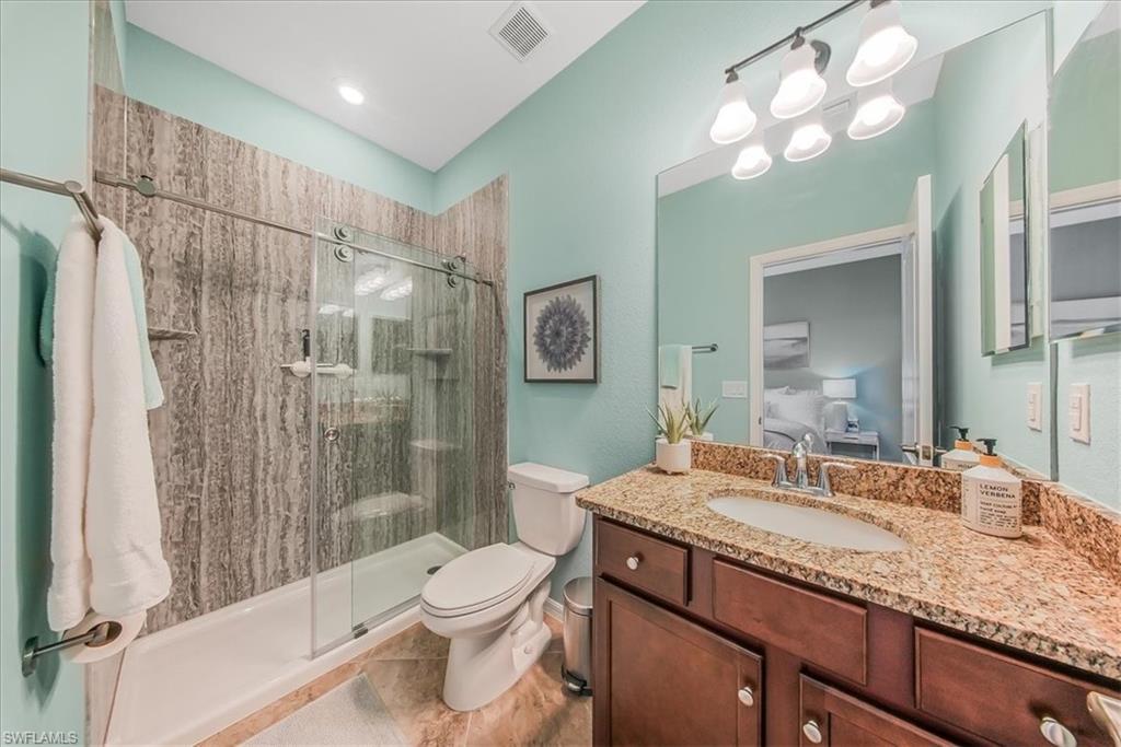 19862 Bittersweet Lane Estero, FL 33928 - Photo 24 of 50 a bathroom with a granite countertop sink toilet a mirror a vanity and shower